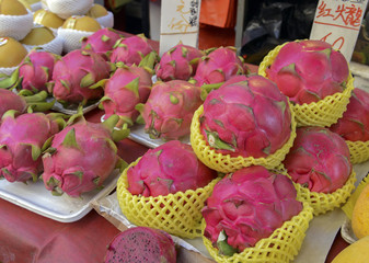 Obraz na płótnie Canvas Street food with dragon fruit among various fresh vegetables for sale at Asian market in China