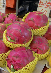 Obraz na płótnie Canvas Street food with dragon fruit among various fresh vegetables for sale at Asian market in China