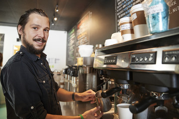 Portrait Of Male Barista Behind Counter In Coffee Shop