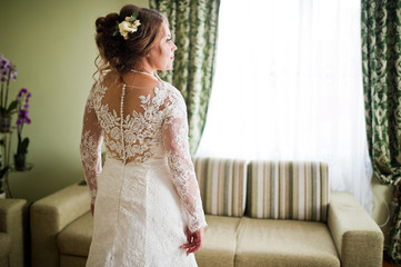 Portrait of a fabulous bride in gorgeous white wedding dress standing alone in the room on her...