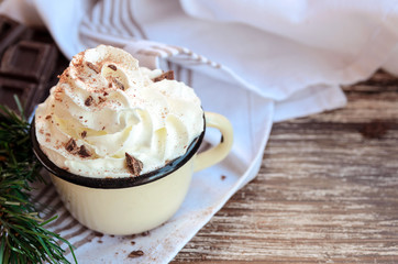 .Metal mug with hot chocolate cocoa with whipped cream and k chocolate crumbs on wooden table.Delicious cold weather beverage concept. Winter times drink background.Copy space.
