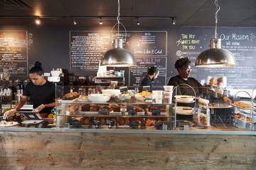 Staff Working Behind Counter In Busy Coffee Shop - Powered by Adobe