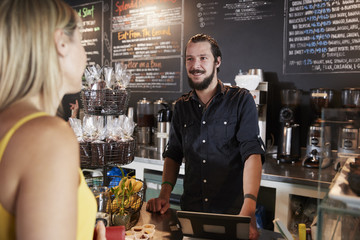 Waiter Taking Female Customer's Order In Coffee Shop