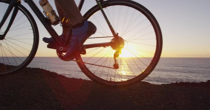 Road bike cyclist sports athlete biking cycling outdoors silhouette close up near ocean. Professional triathlete riding bike on an open road to the sunset. Active healthy man sport lifestyle.