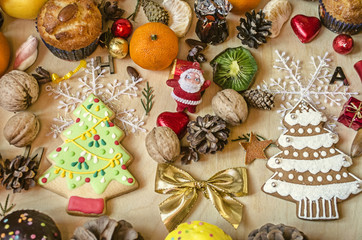 Biscuits spruce and muffins with different pine cones,nuts,citrus fruits and chocolate balls on plywood
 