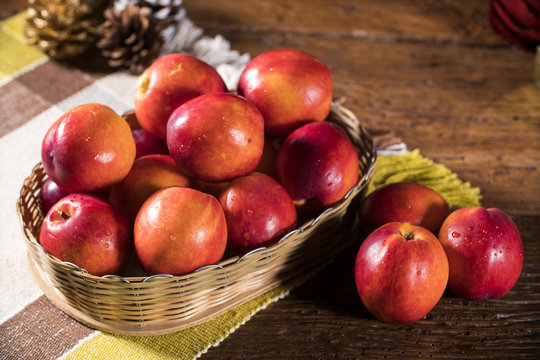 Fresh red nectarines in a wooden bowl.