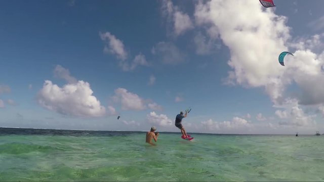 Wide angle shot of kitesurfer riding a foil flying over water in tropical island