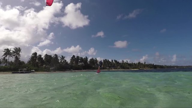 Wide angle shot of kitesurfer riding a foil flying over water in tropical island