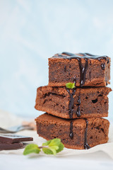 Homemade dark chocolate brownie, a stack of slices with chocolate syrup and mint, space for text