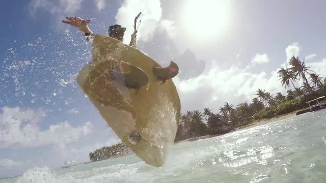 Wide angle shot of kitesurfer riding a surfboard over water in tropical island