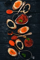 Sandwich with caviar. Caviar on a spoon. On a wooden background. Top view. Free space for text.