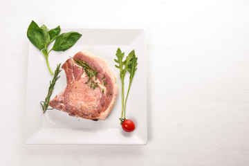 Raw veal steak on a plate. On a wooden background. Top view. Free space for text.