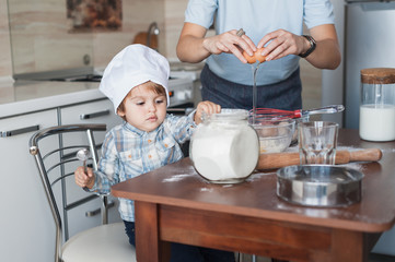 mother and child preparing dough for cookies dough at messy kitchen