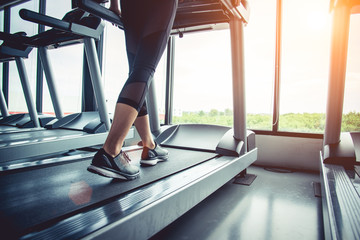 Close up of people who exercising on treadmill. Close-up of woman legs walking by treadmill in...