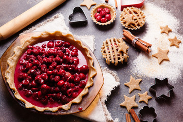Process of cooking cherry pie on black slate background from above