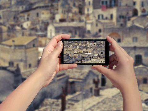Female taking picture of old town Matera in Italy on mobile phone. Landscape of the Matera old town on smart phone. (sassi di Matera)