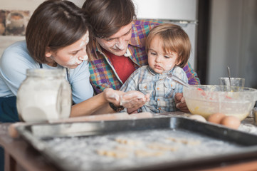 beautiful young family preparing cookies together at kitchen