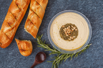 Healthy vegan appetizer, hummus with pine nuts and garlic baguette, dark background
