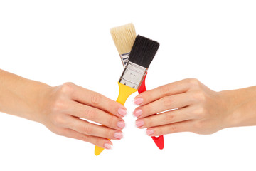 Hands hold two paintbrushes, isolated on white