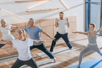 Fototapeta na wymiar senior people with instructor training together on yoga mats in fitness studio