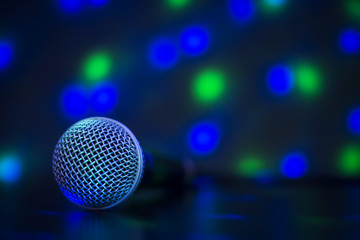 Close up of professional microphone with colorful lights - concert, party, karaoke concept