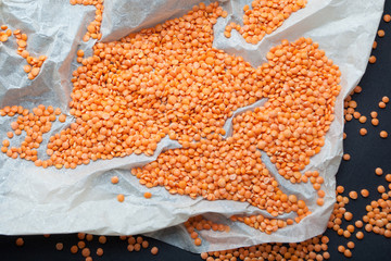 Orange grains of lentils on parchment paper.