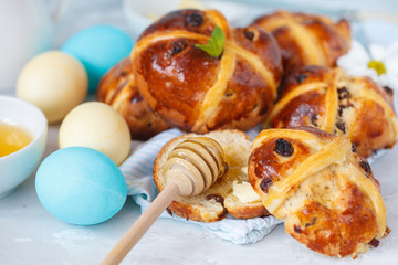 Easter cross buns with honey and butter, painted eggs. Light background, copy space, Easter food concept.
