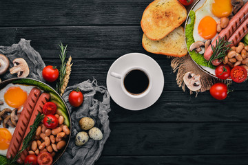 Full English breakfast with fried eggs, sausages, beans, toasts and coffee on copy space background. On a black wooden background.