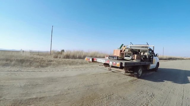 Low Angle Shot Of Small Truck In Rural Dirt Road With Dog In Cage In Back