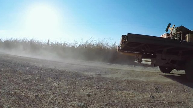 Rustic old truck with dog in cage and old farmer on dirt road close shot