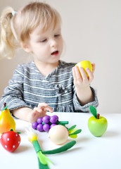 Fototapeta na wymiar Little Girl Playing with Wooden Toys Vegetables Fruits at Home Early Education Preparing for School Development Children Game