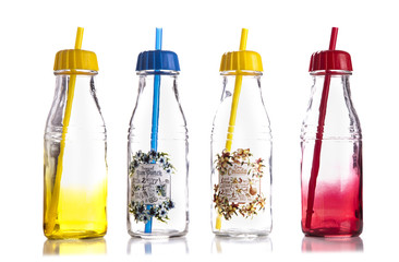 empty colored glass bottles with a lid and a straw on white background,juice bottles isolated