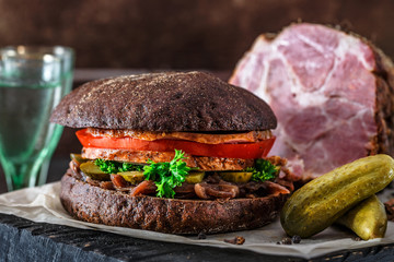 Homemade rye sandwich with ham, tomato, onion, pickles and two glasses of cold vodka.