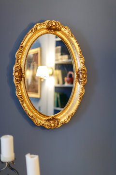 Зеркало в золотой оправе на стене