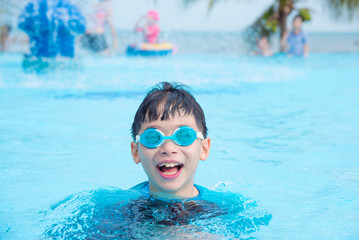 Naklejka premium Young asian boy wearing goggles swimming in outdoor swimming pool
