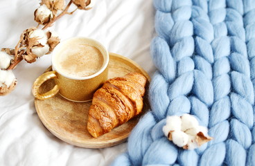 Cup with cappuccino, croissant, blue pastel giant plaid, bedroom, morning concept, cotton flower 