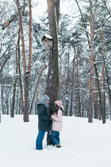 Fototapeta na wymiar young couple looking at each other while standing in winter forest