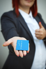 Concept of purchases, banking services. A woman in a suit and glasses points and passes a credit card. With a place for advertising text.