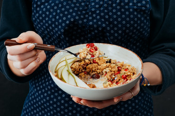 cropped image of female cook holding bowl with granola and spoon in hands