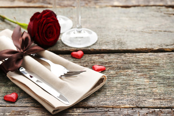 Kitchen cutlery with napkin and red rose on wooden table
