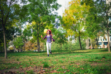 Young woman with colorful balloons running in the park.
