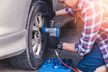 The asian technician use a air wrench for replacement the wheel in the garage. the concept of automotive, repairing, mechanical, vehicle and technology.