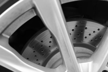 Brake disc of a sports car with holes for ventilation and cooling - black and white