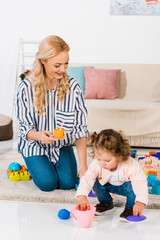 Obraz premium happy mother and daughter playing with plastic cups