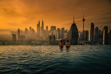 Fotobehang Twee reiziger man op zoek naar de skyline van de stad Kuala Lumpur in het zwembad op het dak van het hotel bij zonsopgang in Kuala Lumpur, Maleisië. © nuttawutnuy
