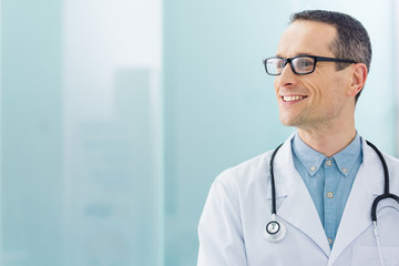 smiling doctor in white coat with stethoscope in hospital