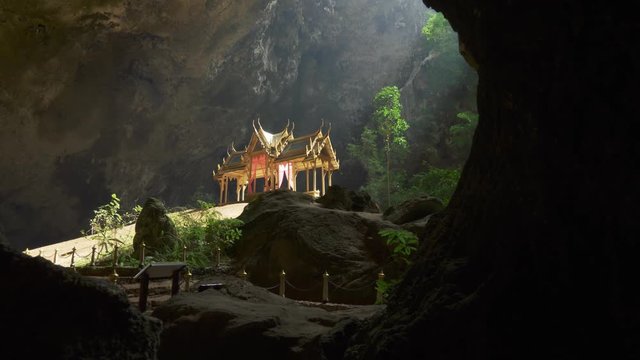 Phraya Nakhon Cave. Khao Sam Roi Yot National Park in Thailand. Sunbeam on golden Buddhist pavilion. Gimbal shot, 4K
