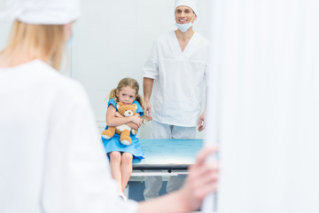 doctors preparing scared kid for surgery in operating room