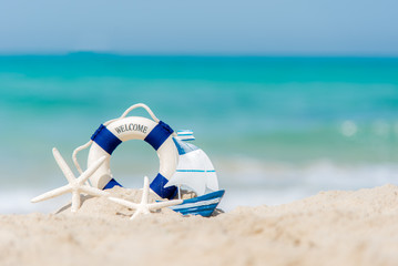 Lifebuoy on sand beach background with starfish and fishing boat, copy space.  Summer Concept