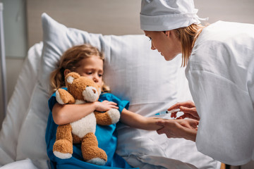 female doctor making vaccination to scared kid